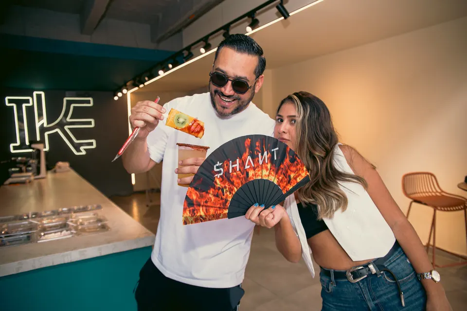 Clientes con paletas IKE dentro del local de Laureles, con el logo en neón al fondo