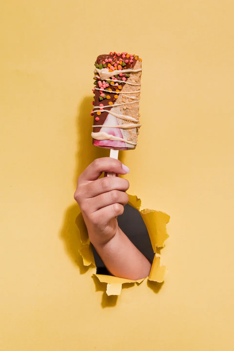 Paleta cremosa IKE nivel La Escandalosa con dos baños y toppings, sobre fondo amarillo