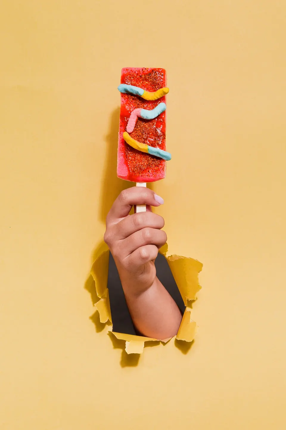 Paleta frutal IKE nivel La Escandalosa con cuatro toppings ácidos y gomitas, sobre fondo amarillo